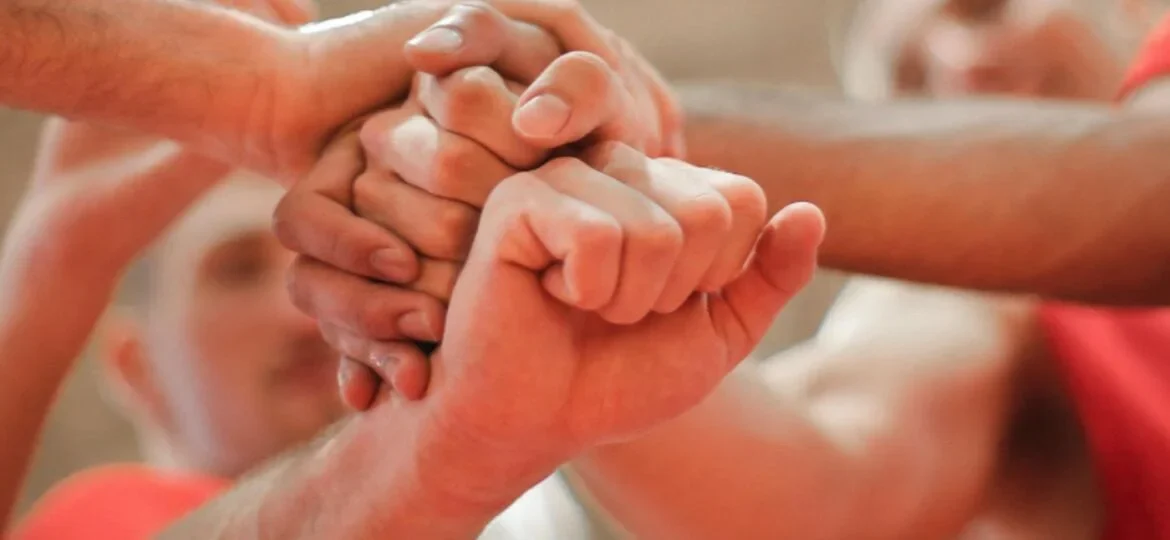 Teamwork in action as multiple hands come together in a unified gesture, symbolising collaboration and support among team members.