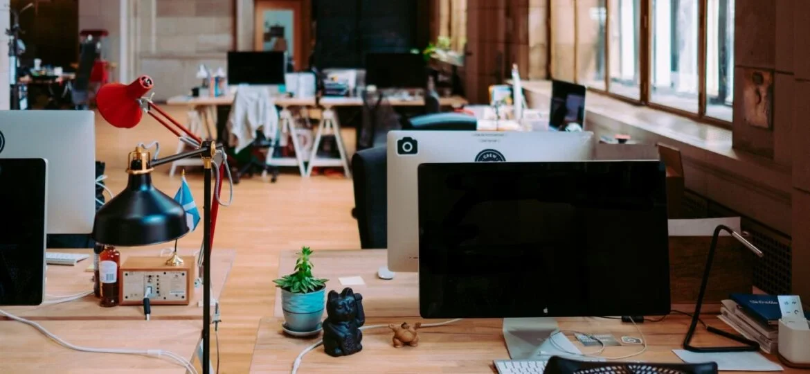 Spacious, eclectic office space with a variety of workstations and personal touches, illustrating a dynamic and creative work environment.