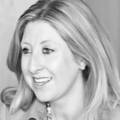 Black and white photo of a smiling woman with shoulder-length hair, wearing a necklace.